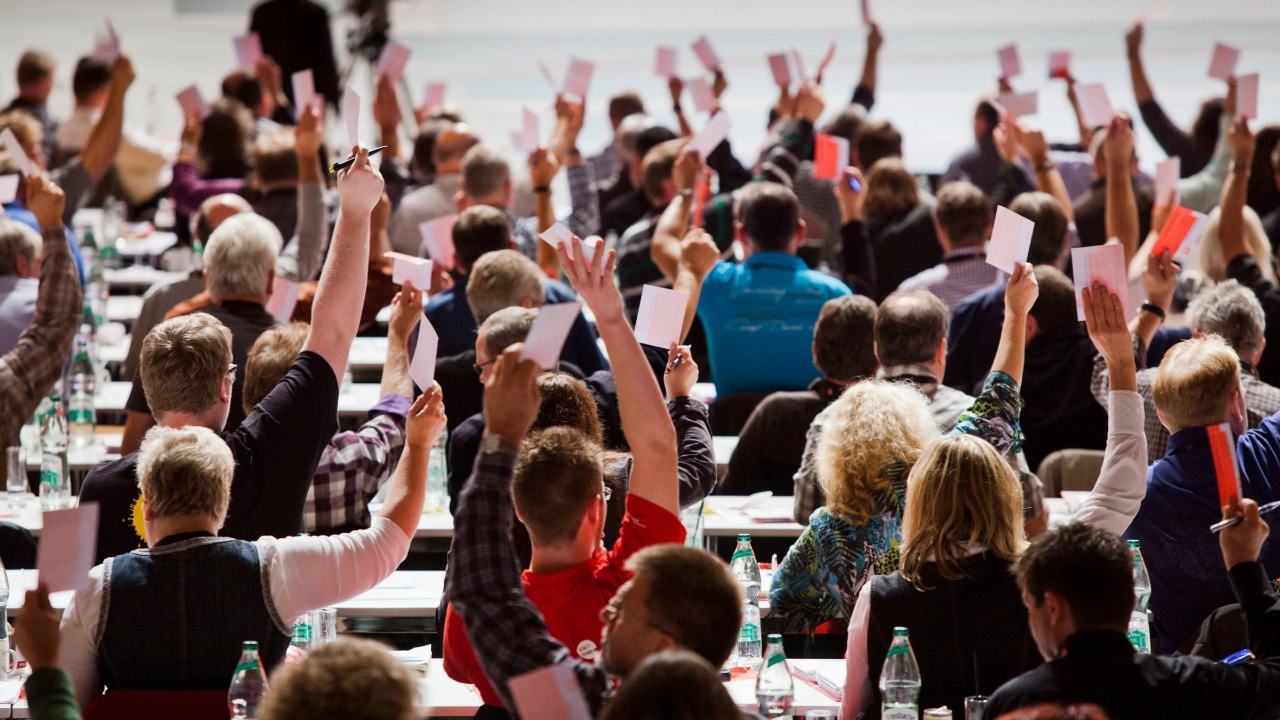 Menschen heben die Hände bei einer Abstimmung.